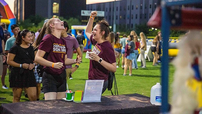 Kinesiology senior Cosette Reimann and her sister Savannah Reimann (left) knock down targets during the Polypalooza carnival on the Polytechnic campus on Aug. 15, 2021