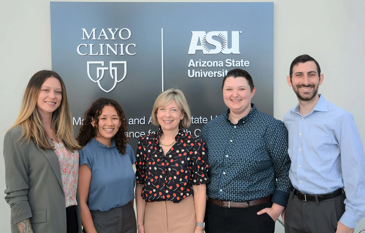 Five people stand in front of a blue-gray sign with the Mayo Clinic and ASU logos.