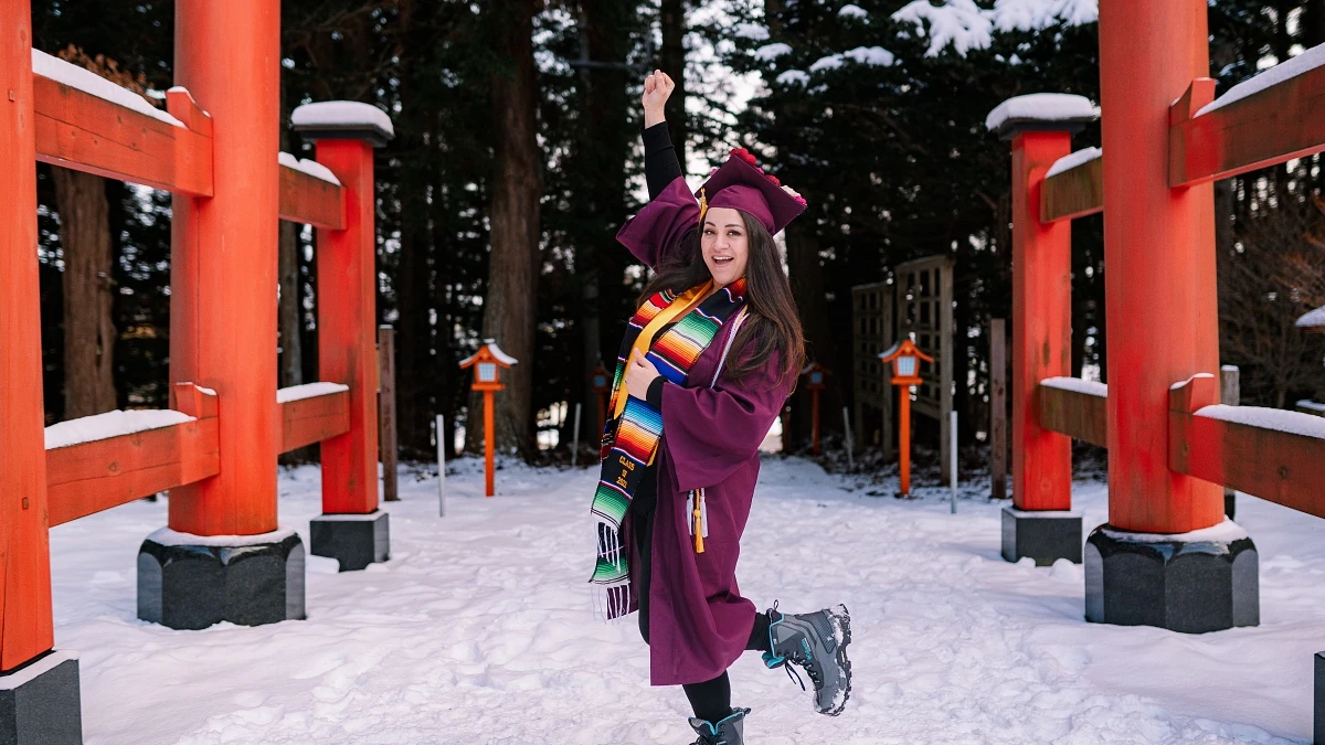 Shannon Zellner standing in snow in grad attire.