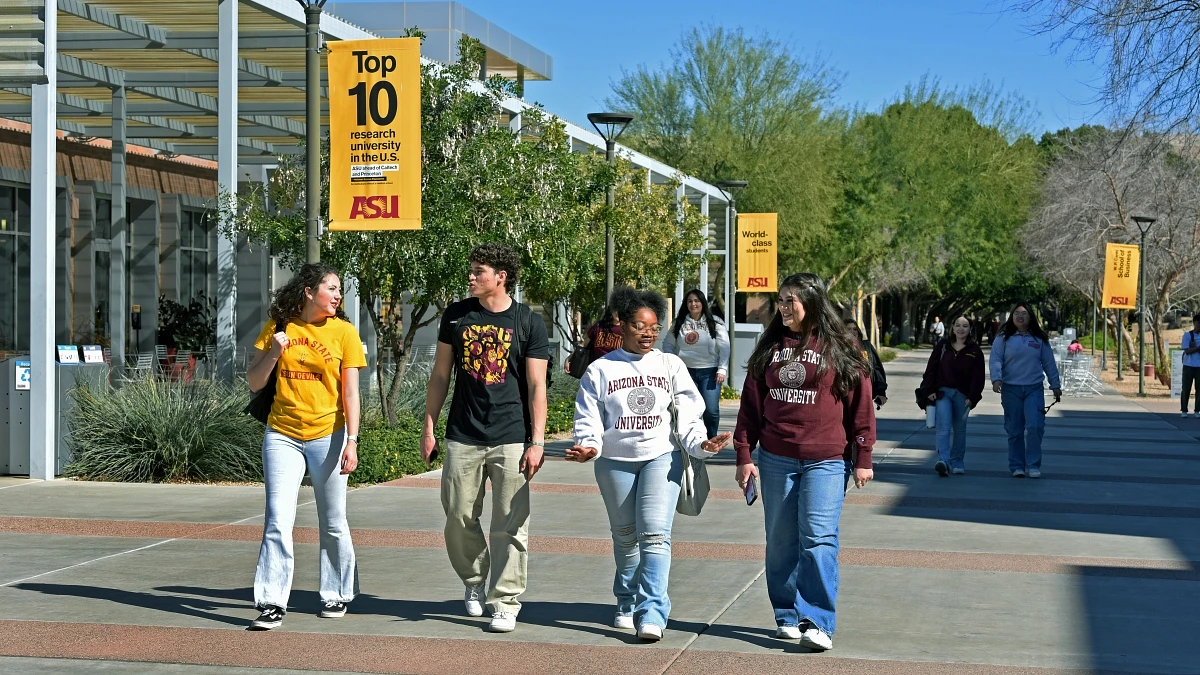 A group of students walks on a university campus under banners highlighting the school's top research ranking.Photo by Tim Trumble Photography 