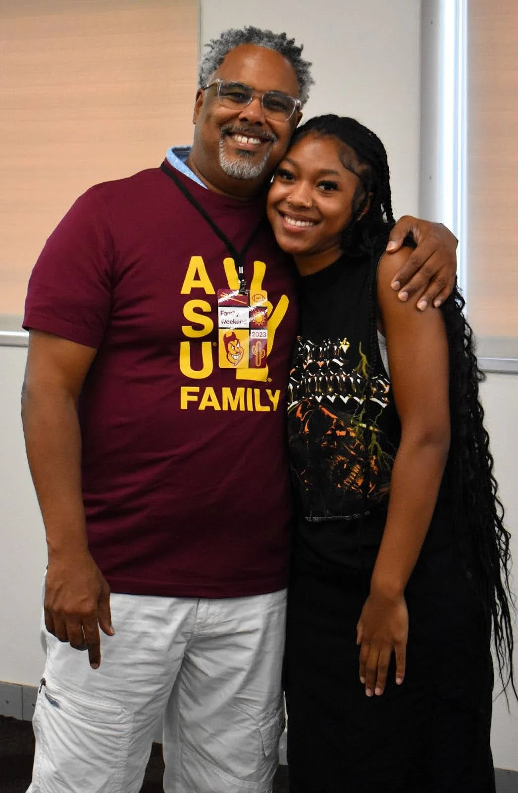 A smiling man and woman pose together, with the man wearing a maroon ASU Family t-shirt.