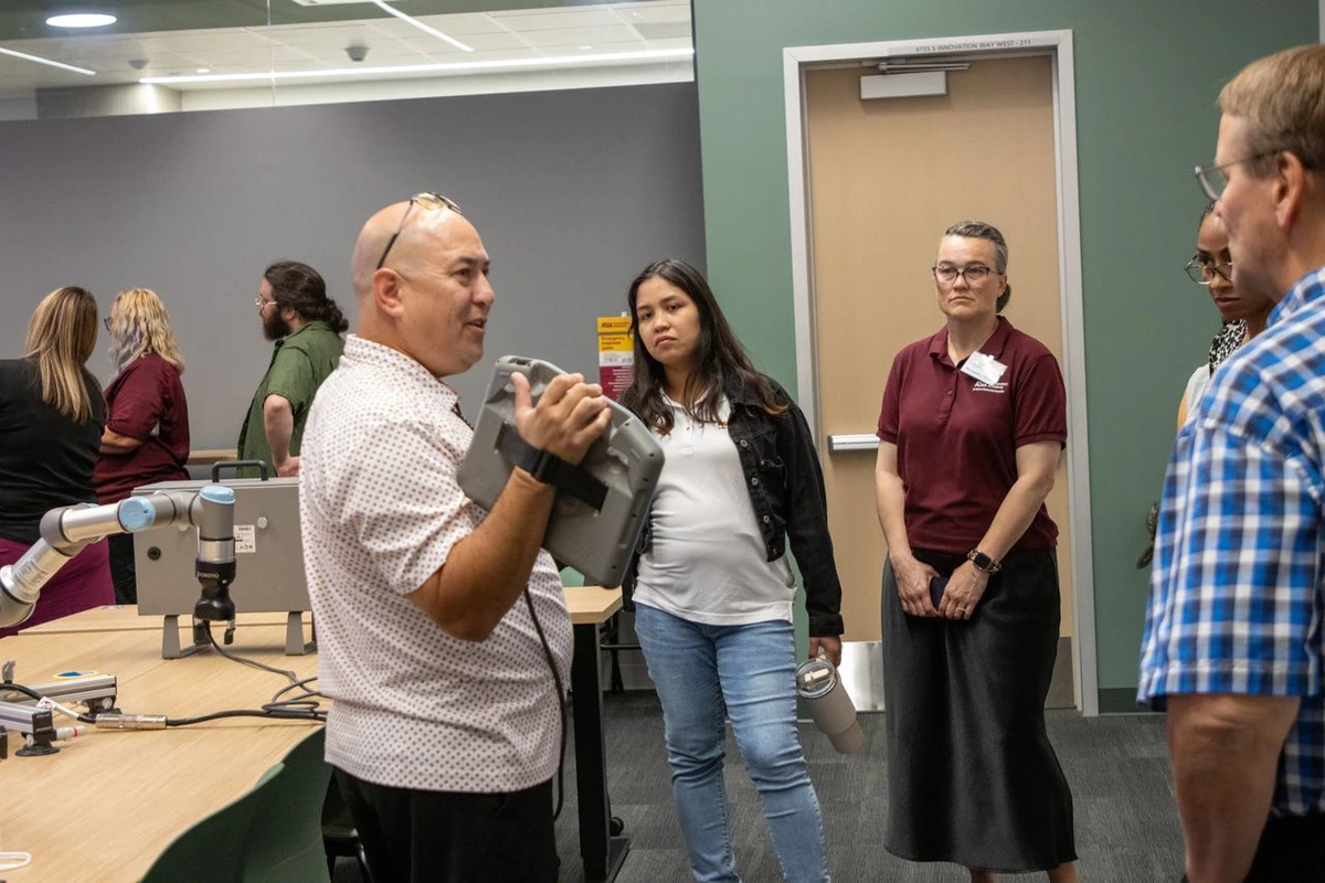 A group of educators watch a demonstration about semiconductors and other machinery.